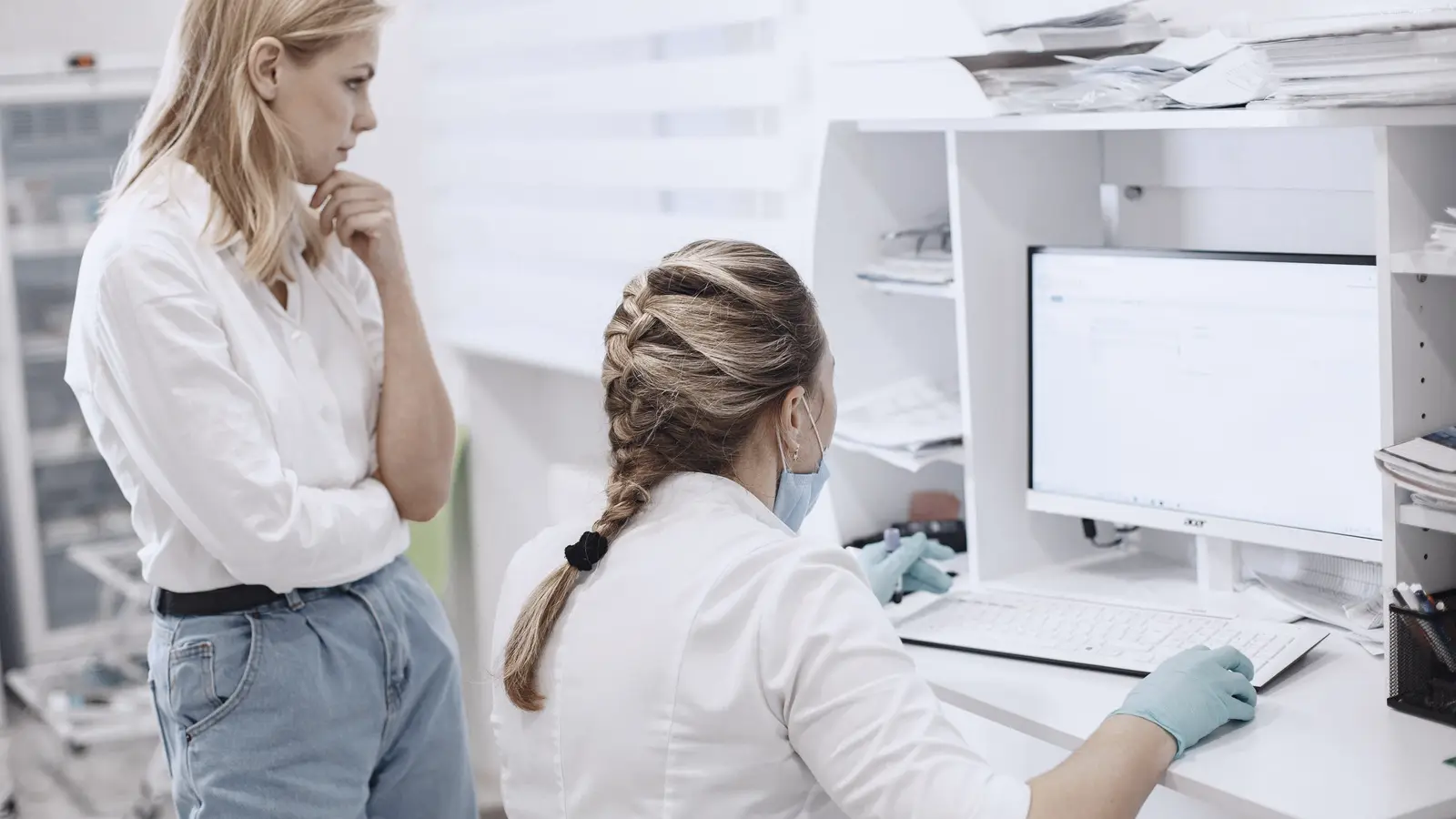 Twee zorgmedewerkers bekijken samen patiëntgegevens op een computer bij een kliniekbalie