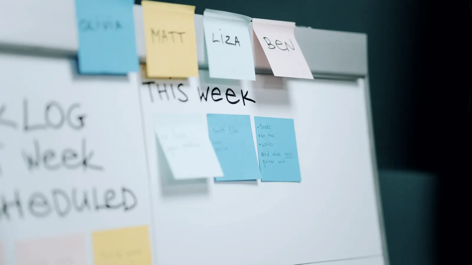 Whiteboard met memoblaadjes per teamlid onder de kop This Week