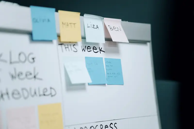Whiteboard met memoblaadjes per teamlid onder de kop This Week